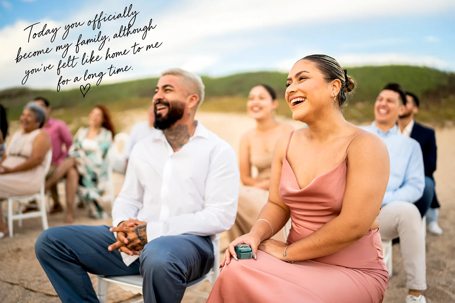 Wedding guests smiling during the ceremony with a handwritten wedding vow about becoming family and feeling at home together.